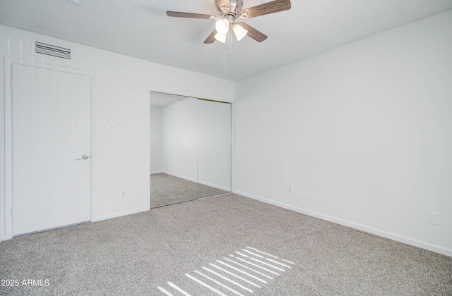 unfurnished bedroom with ceiling fan, a textured ceiling, a closet, and carpet flooring