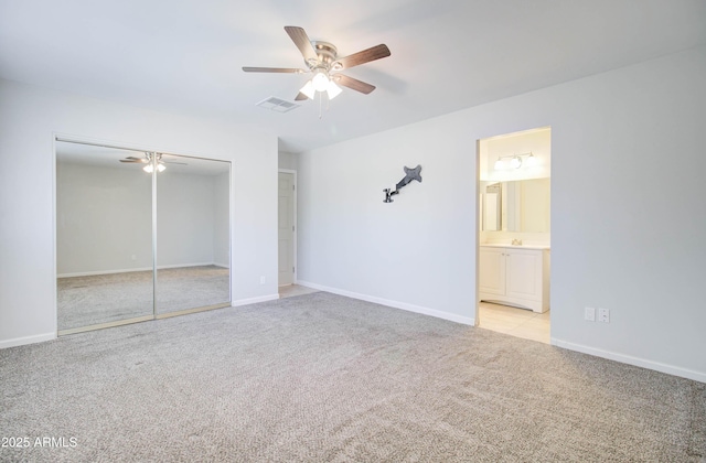 unfurnished bedroom with ceiling fan, light colored carpet, and ensuite bath