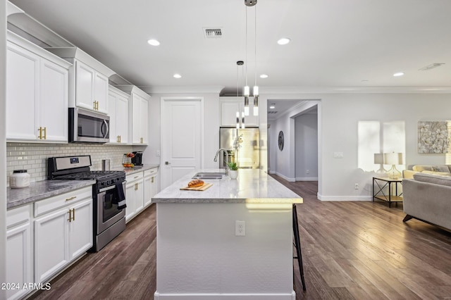 kitchen featuring pendant lighting, decorative backsplash, a center island with sink, white cabinets, and appliances with stainless steel finishes