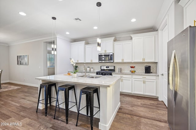 kitchen with appliances with stainless steel finishes, a kitchen island with sink, hanging light fixtures, and sink