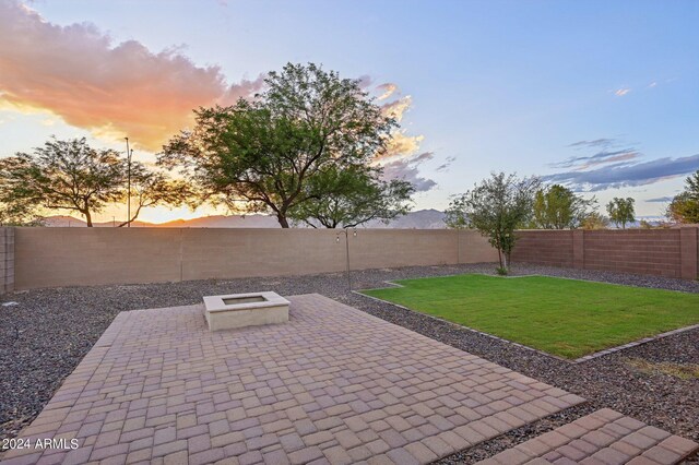 patio terrace at dusk featuring a yard and a fire pit