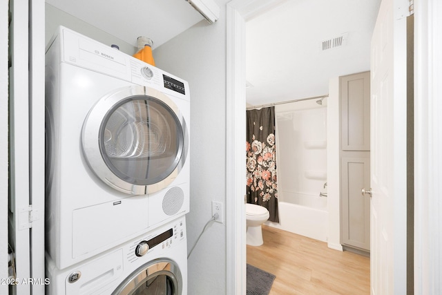 washroom featuring stacked washer / dryer and light wood-style flooring