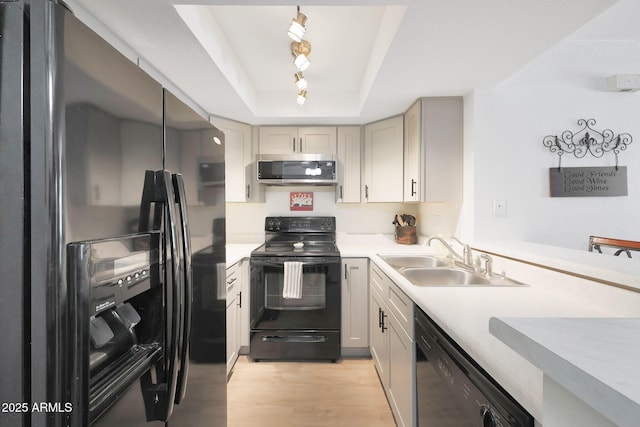 kitchen featuring black appliances, a sink, a raised ceiling, light countertops, and track lighting