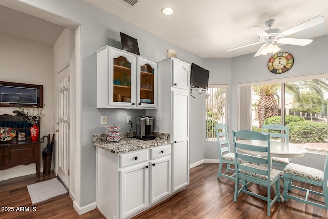 16331 W Tierra Way, Surprise, AZ 85374 - kitchen with light stone counters, glass insert cabinets, baseboards, white cabinets, and dark wood-style flooring