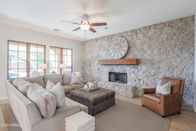 living room with ceiling fan, visible vents, a fireplace, and wood finished floors