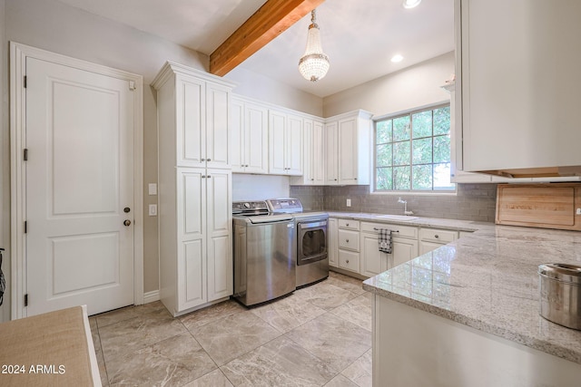 kitchen with backsplash, washing machine and dryer, white cabinets, light stone countertops, and beamed ceiling