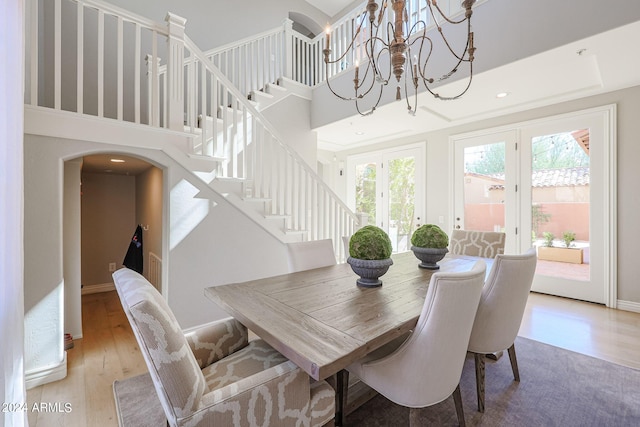 dining area with arched walkways, a high ceiling, wood finished floors, baseboards, and stairs