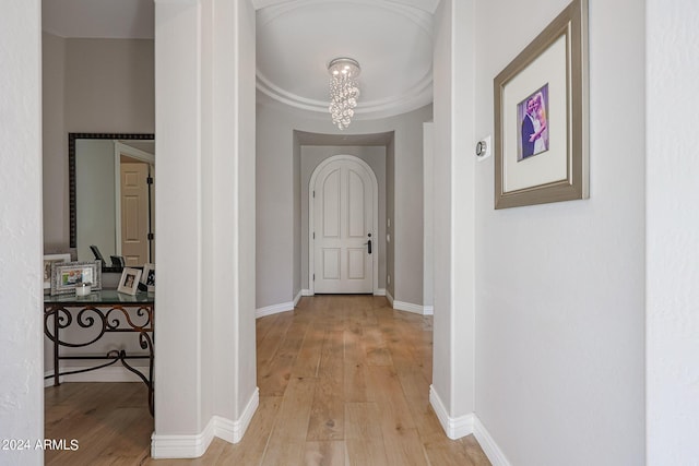 hall with a chandelier, baseboards, and light wood finished floors