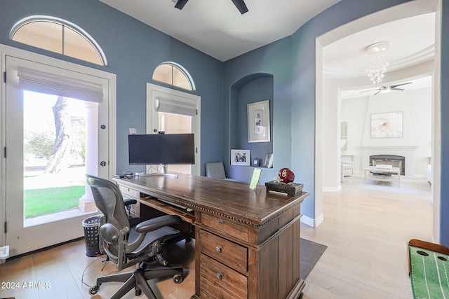 home office with light wood-style flooring, a fireplace, a ceiling fan, and baseboards