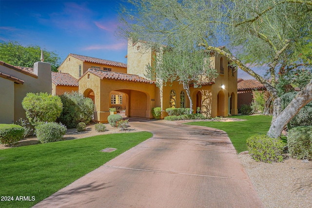 mediterranean / spanish-style house with stucco siding, a tiled roof, concrete driveway, and a front yard