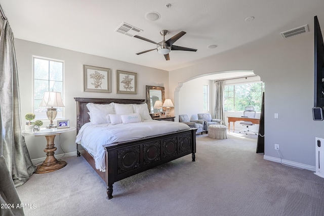 carpeted bedroom with arched walkways, visible vents, and baseboards