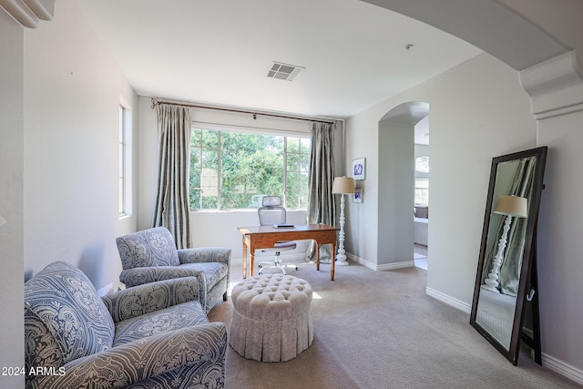 living area with carpet floors, visible vents, arched walkways, and baseboards