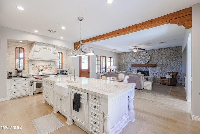 kitchen featuring a fireplace, visible vents, an accent wall, a sink, and high end range