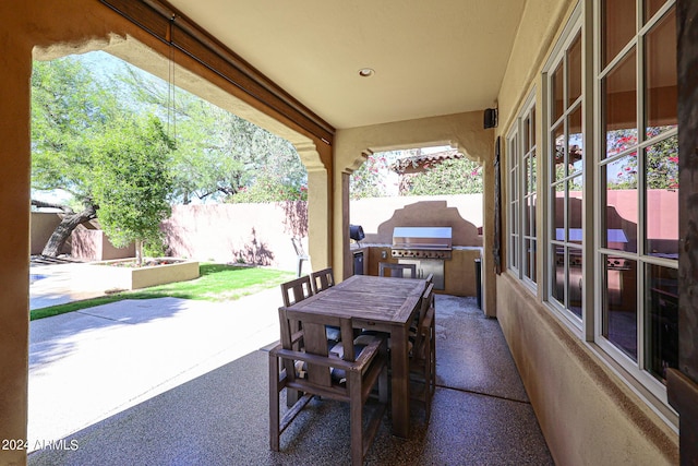 view of patio / terrace with outdoor dining space, fence, grilling area, and an outdoor kitchen