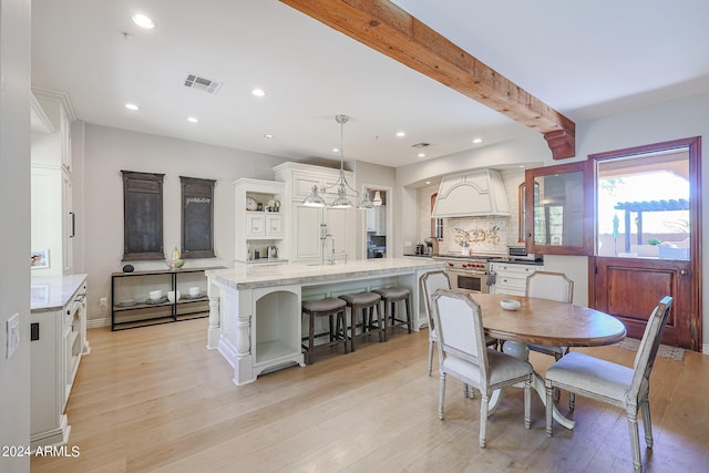 dining area featuring light wood-type flooring, visible vents, and beamed ceiling