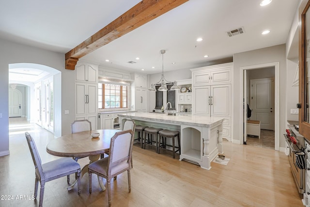 dining area featuring arched walkways, beam ceiling, recessed lighting, visible vents, and light wood-type flooring