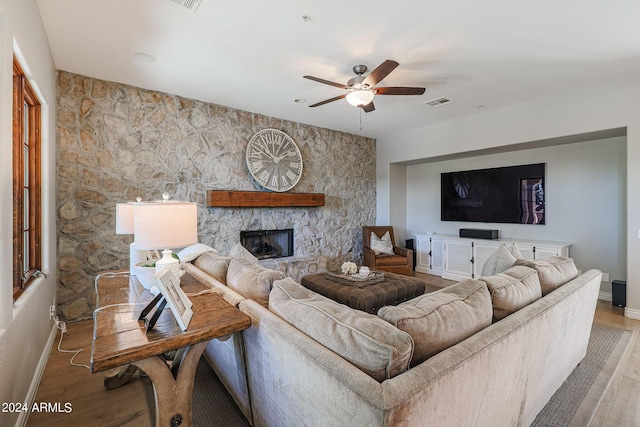 living area with ceiling fan, a fireplace, wood finished floors, and baseboards