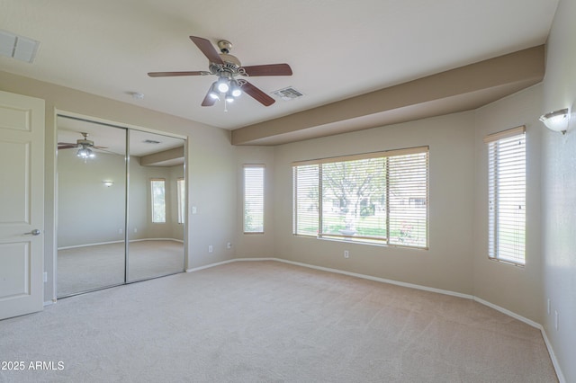 unfurnished bedroom with ceiling fan, light colored carpet, and a closet