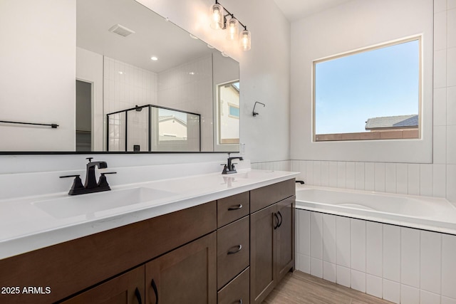 bathroom featuring double vanity, a sink, a bath, and a shower stall