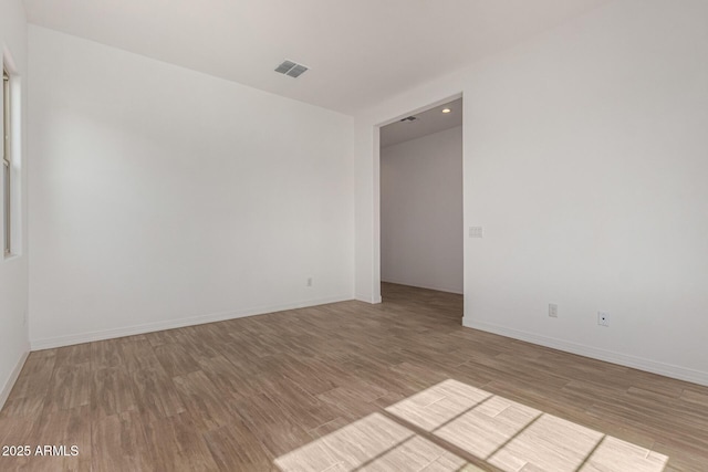 spare room with visible vents, baseboards, and wood finished floors