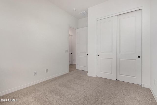 unfurnished bedroom with carpet floors, a closet, visible vents, and baseboards