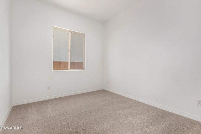 spare room featuring carpet floors and baseboards