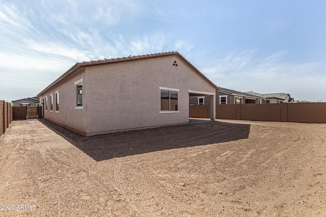 rear view of property featuring a tile roof, a fenced backyard, and stucco siding