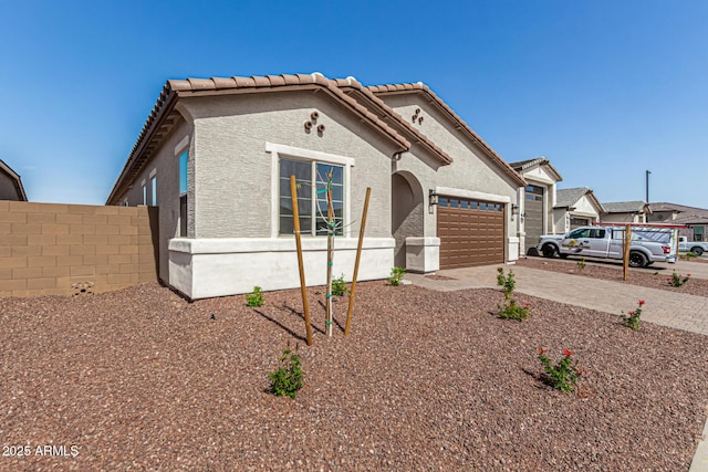 view of front of house with a garage, concrete driveway, a tiled roof, fence, and stucco siding