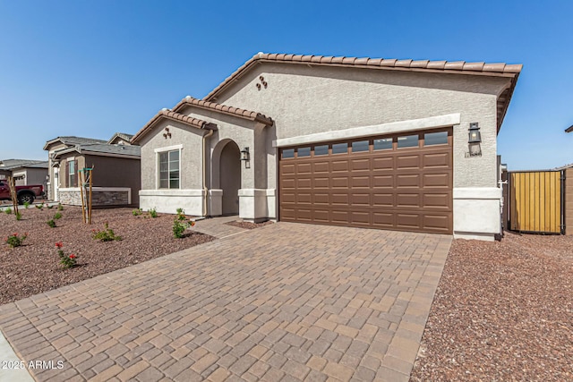 view of front of property featuring a tiled roof, decorative driveway, an attached garage, and stucco siding