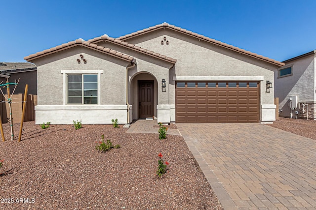 view of front of home with a garage, decorative driveway, a tile roof, and stucco siding