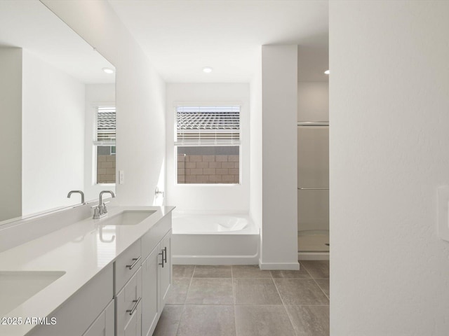 bathroom with double vanity, a sink, a bath, and recessed lighting