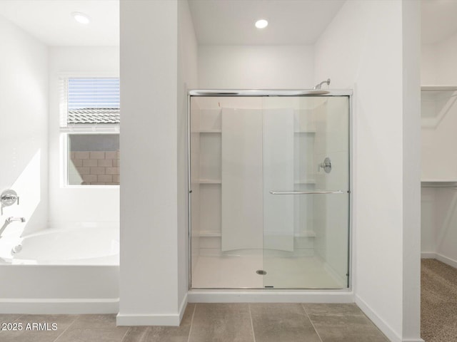 full bathroom featuring baseboards, a stall shower, a bath, and a walk in closet