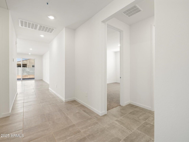 hallway featuring baseboards, visible vents, and light tile patterned floors