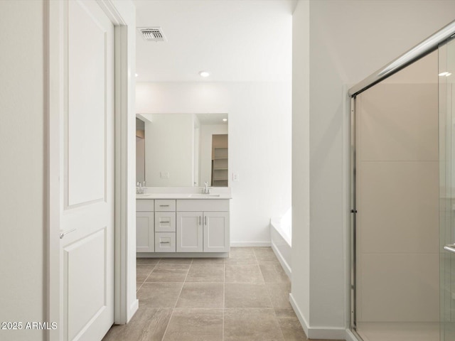 bathroom with visible vents, double vanity, baseboards, a shower stall, and a sink