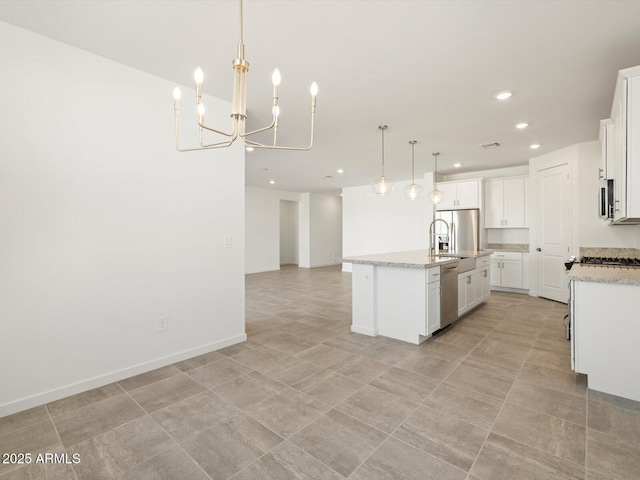 kitchen with a chandelier, appliances with stainless steel finishes, open floor plan, white cabinetry, and an island with sink