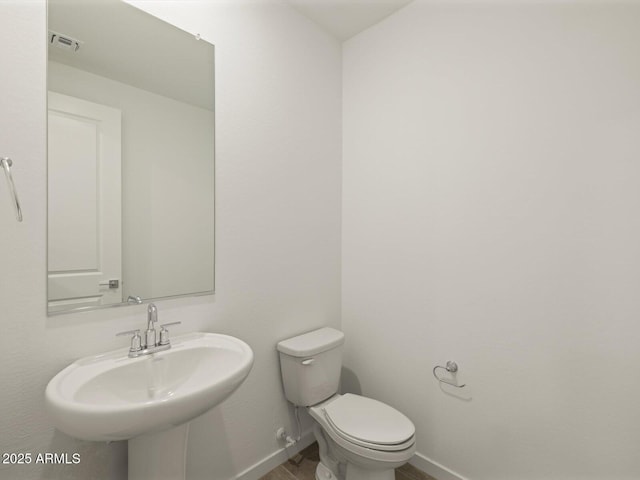 bathroom with a sink, baseboards, toilet, and visible vents