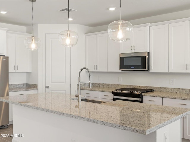 kitchen featuring stainless steel appliances, pendant lighting, a sink, and an island with sink