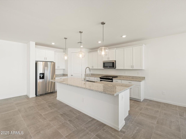 kitchen with a center island with sink, white cabinets, appliances with stainless steel finishes, decorative light fixtures, and a sink