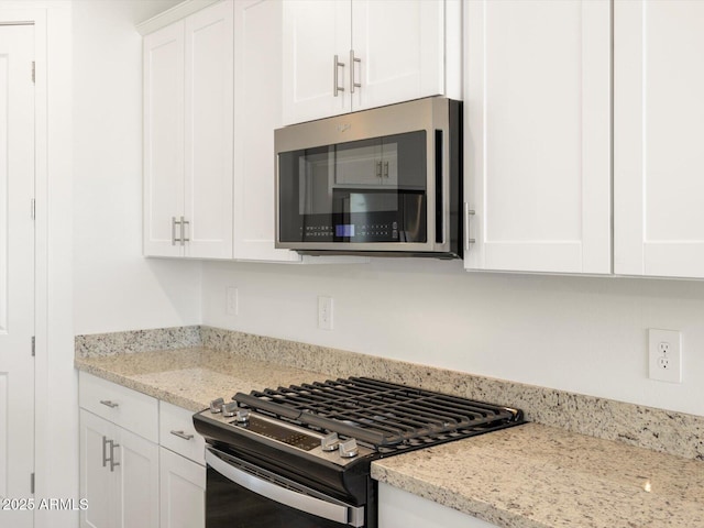 kitchen with appliances with stainless steel finishes, white cabinets, and light stone counters