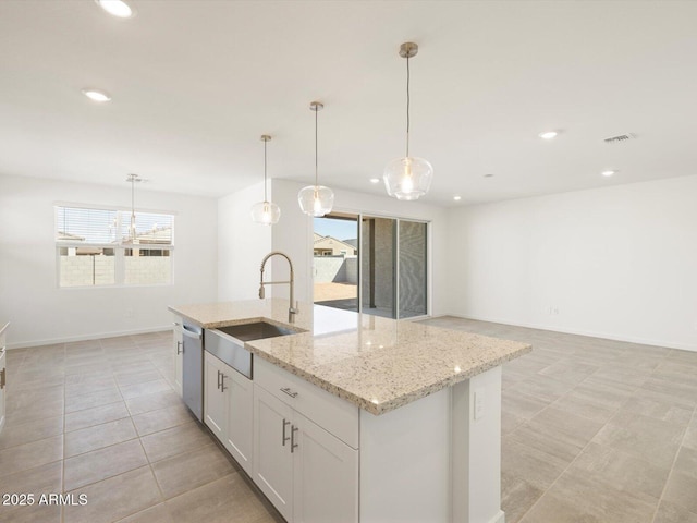 kitchen featuring a sink, white cabinets, hanging light fixtures, stainless steel dishwasher, and a center island with sink