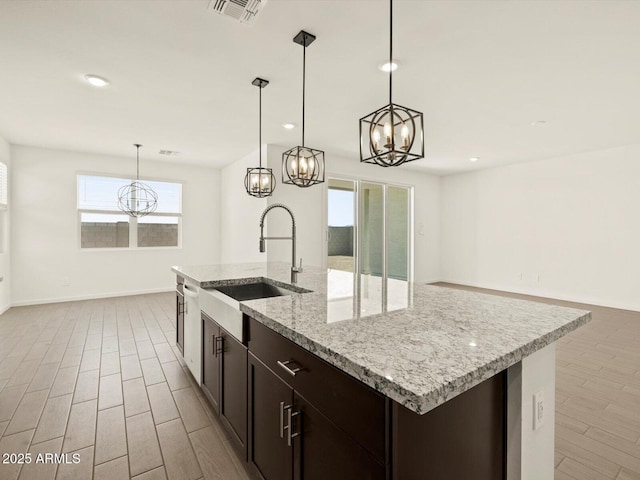 4035 S 176th Dr, Goodyear, AZ 85338 - kitchen with a chandelier, light wood finished floors, decorative light fixtures, dark brown cabinets, and a center island with sink
