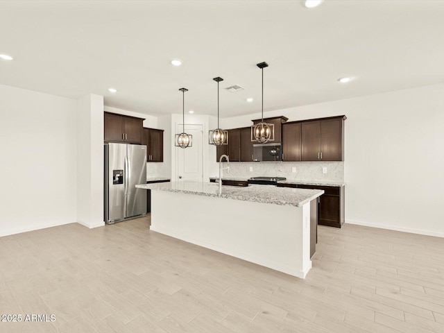 4035 S 176th Dr, Goodyear, AZ 85338 - kitchen with stainless steel fridge with ice dispenser, dark brown cabinets, decorative backsplash, black microwave, and a kitchen island with sink