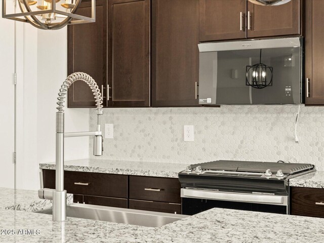 4035 S 176th Dr, Goodyear, AZ 85338 - kitchen with a chandelier, range with electric stovetop, stainless steel microwave, dark brown cabinets, and tasteful backsplash
