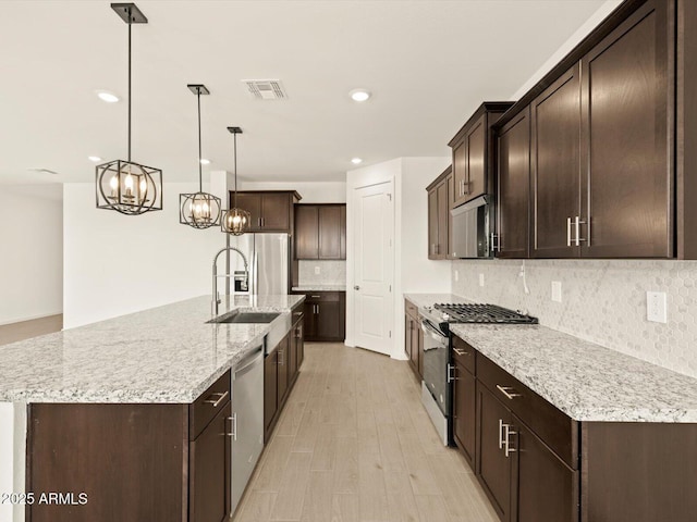 4035 S 176th Dr, Goodyear, AZ 85338 - kitchen with stainless steel appliances, dark brown cabinetry, decorative backsplash, a chandelier, and recessed lighting
