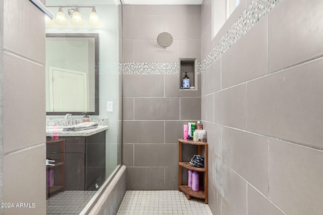 bathroom featuring tiled shower, vanity, tile patterned flooring, and tile walls