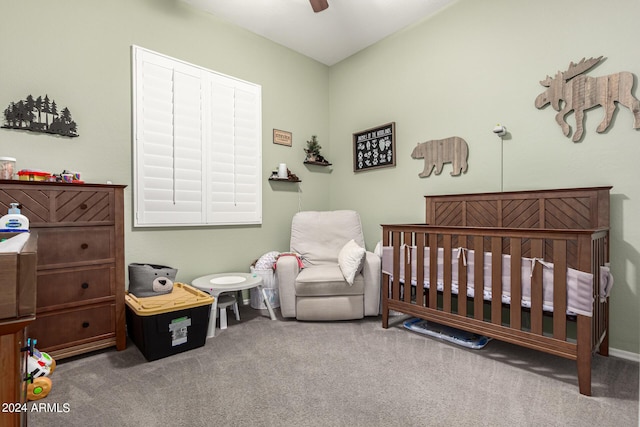 bedroom featuring a nursery area, ceiling fan, and carpet