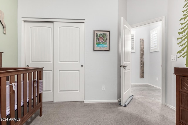 bedroom with a nursery area, light carpet, and a closet