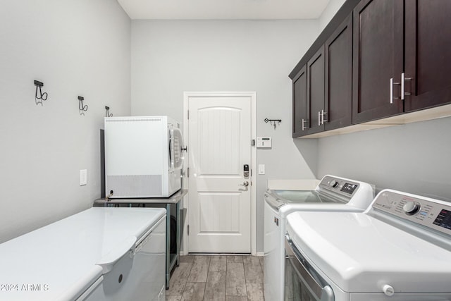 clothes washing area featuring washing machine and dryer and cabinets