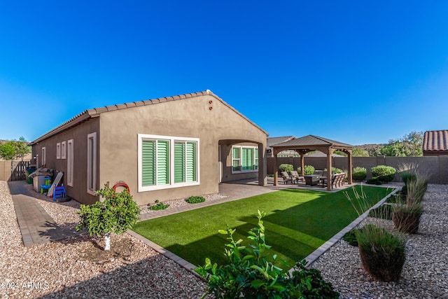 rear view of property with a gazebo, a yard, and a patio