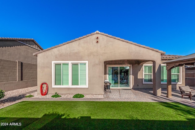 rear view of property featuring a patio and a lawn